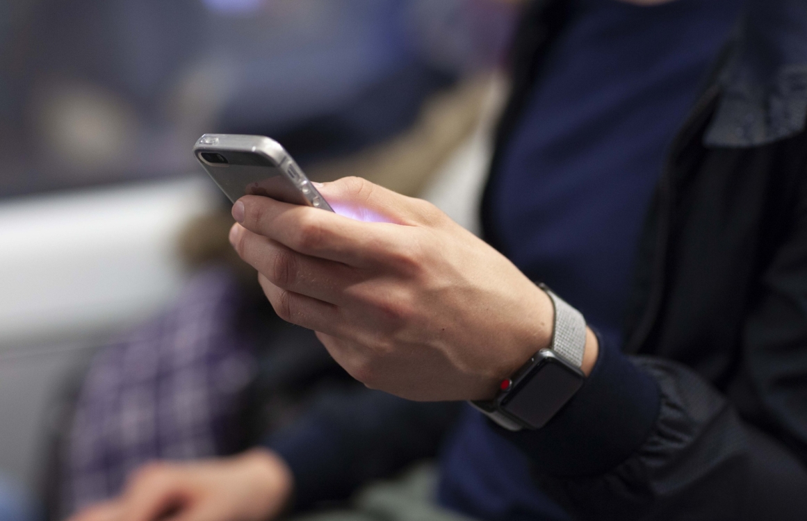 Mann mit Smartwatch am Handgelenk und Smartphone in der Hand Detailansicht