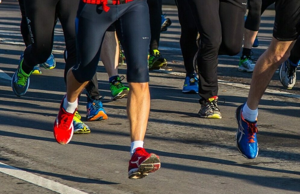 Blick auf Beine und Füße mehrerer Jogger beim Laufen auf der Straße