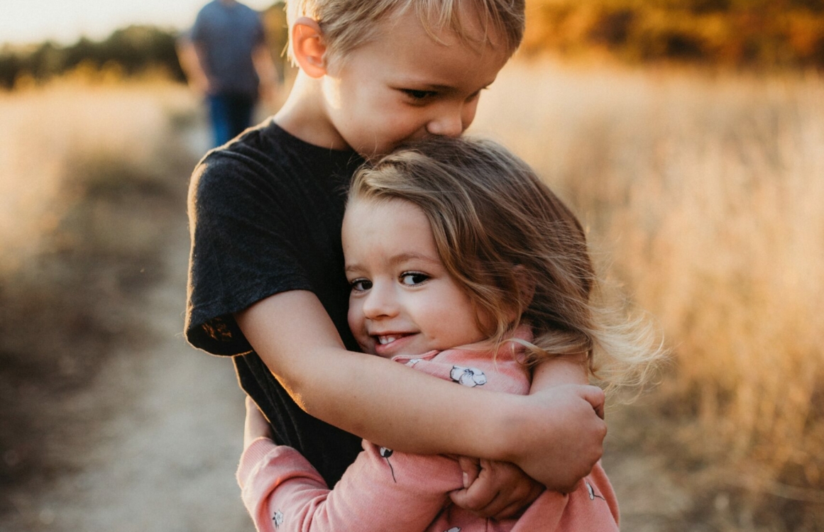 Kleiner Junge und kleines Mädchen umarmen sich liebevoll