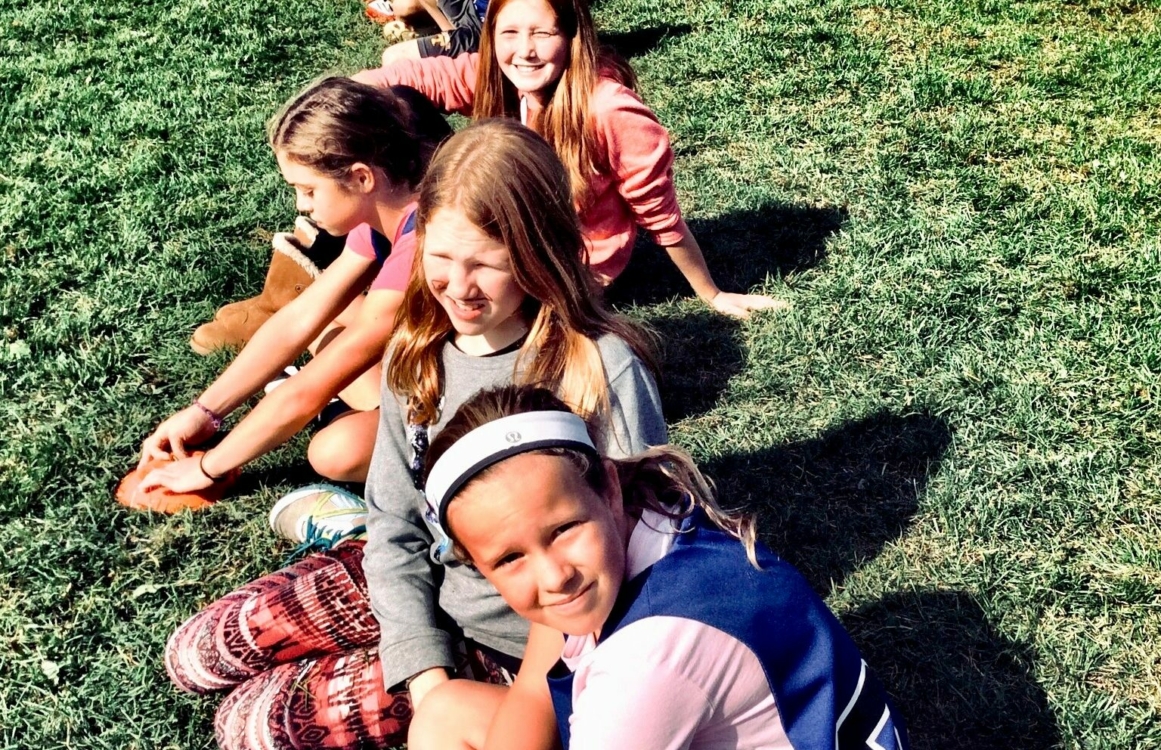 Kinder sitzen nebeneinander auf einer Wiese