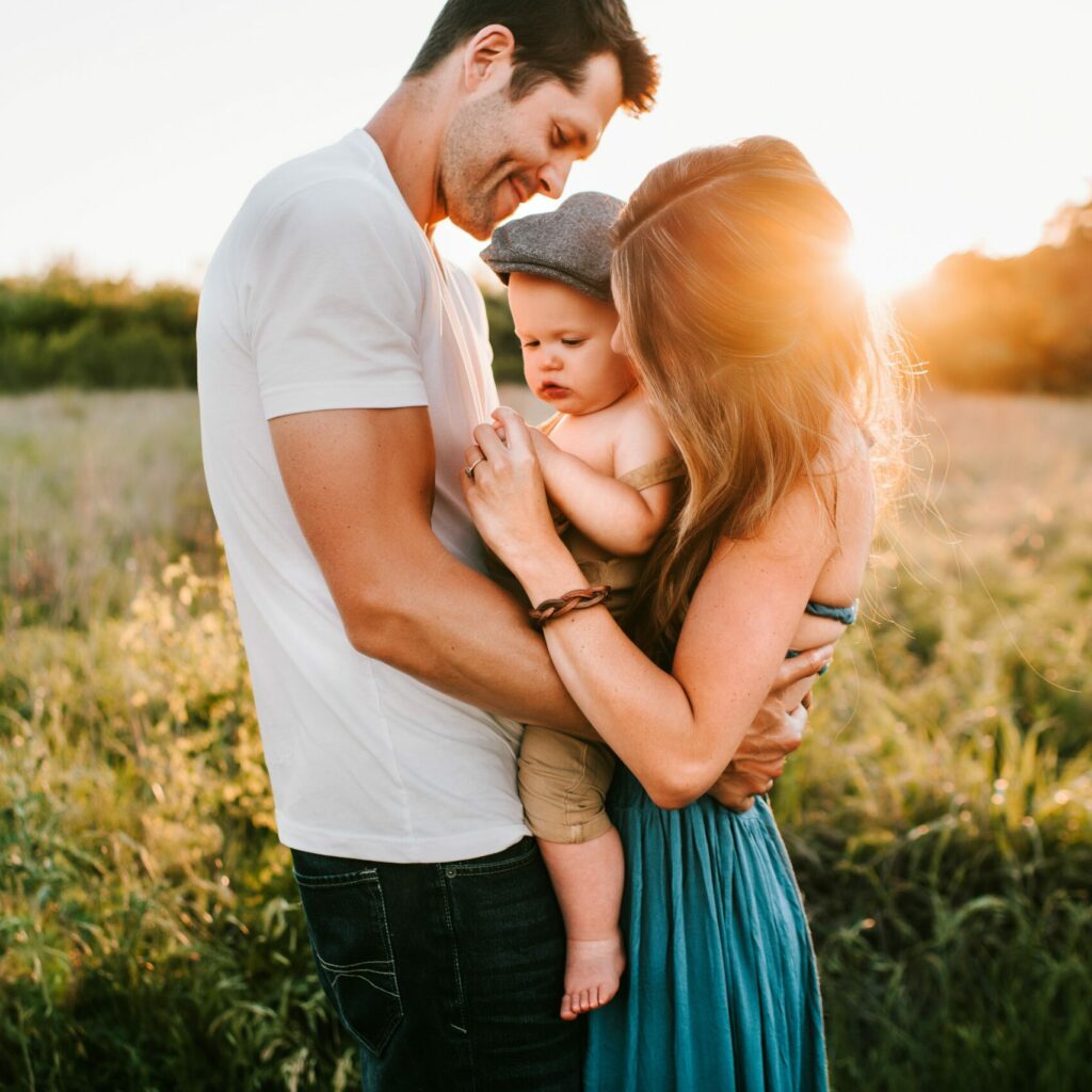 Eltern mit Kind im Arm einer einer Wiese