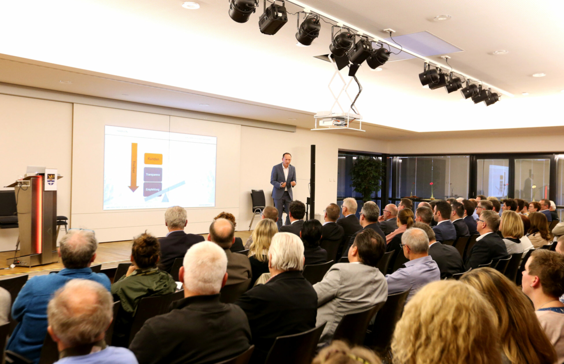 Referent bei einem Vortrag vor mehreren Zuschauerinnen und Zuschauern