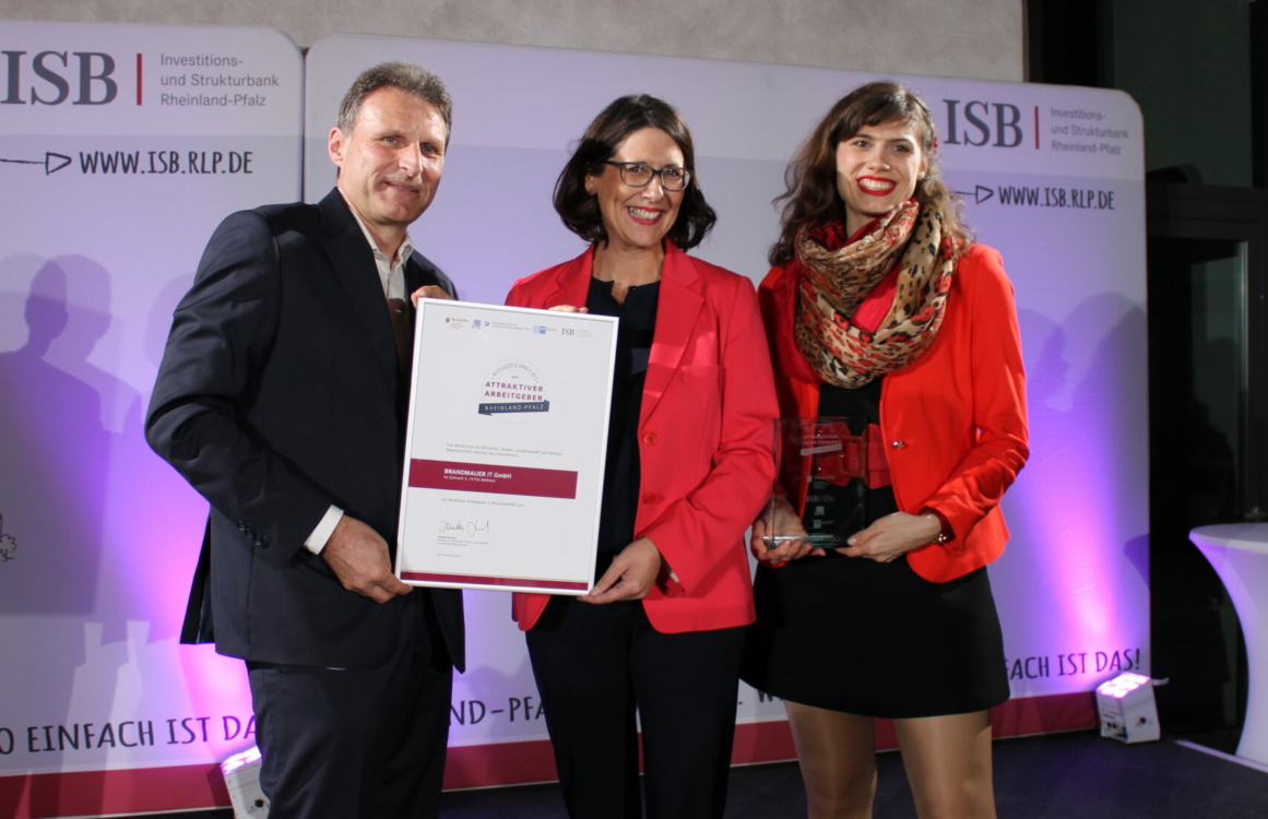 Drei Menschen bei der Übergabe einer Urkunde auf der Bühne